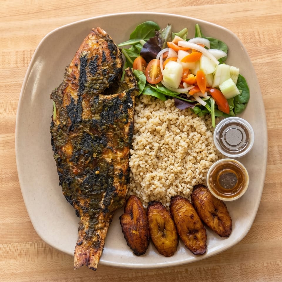 Grilled whole fish with rice, fried plantains, a fresh salad, and two dipping sauces.