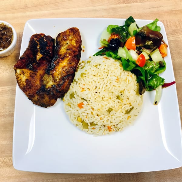 Grilled fish with rice, a side salad, and a small dish of sauce on a white plate.